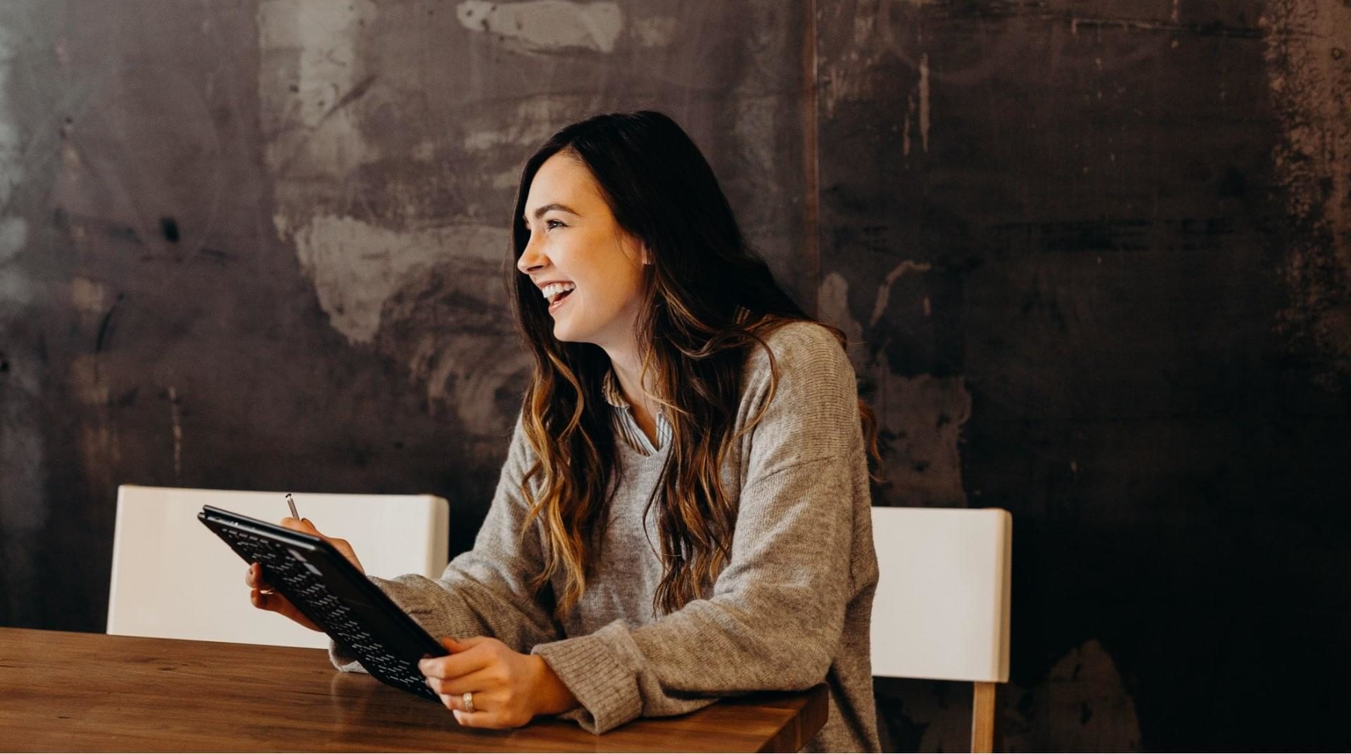 woman laughing while using a tablet